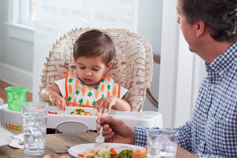 Toddler looking down at their food while parent talks