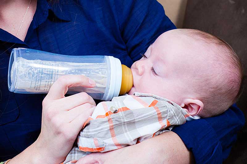 Mamá alimentando al bebé con un biberón