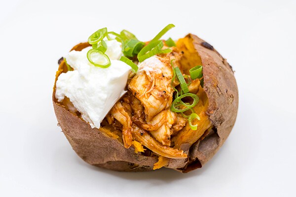 A photo of the BBQ chicken stuffed sweet potato recipe topped with Greek yogurt and chives.