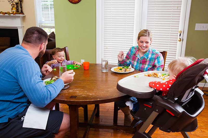 Familia cenando con dos niños.