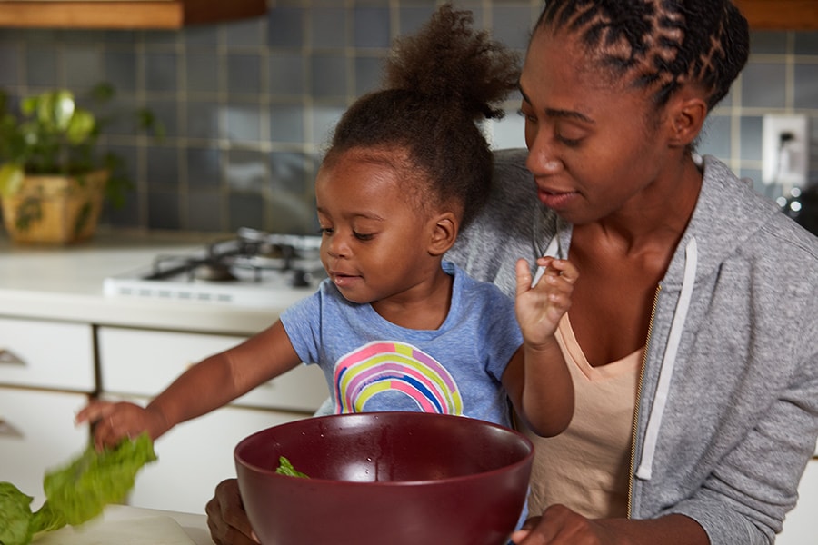 Toddler grabbing lettuce to help with an easy tofy taco bowl recipe