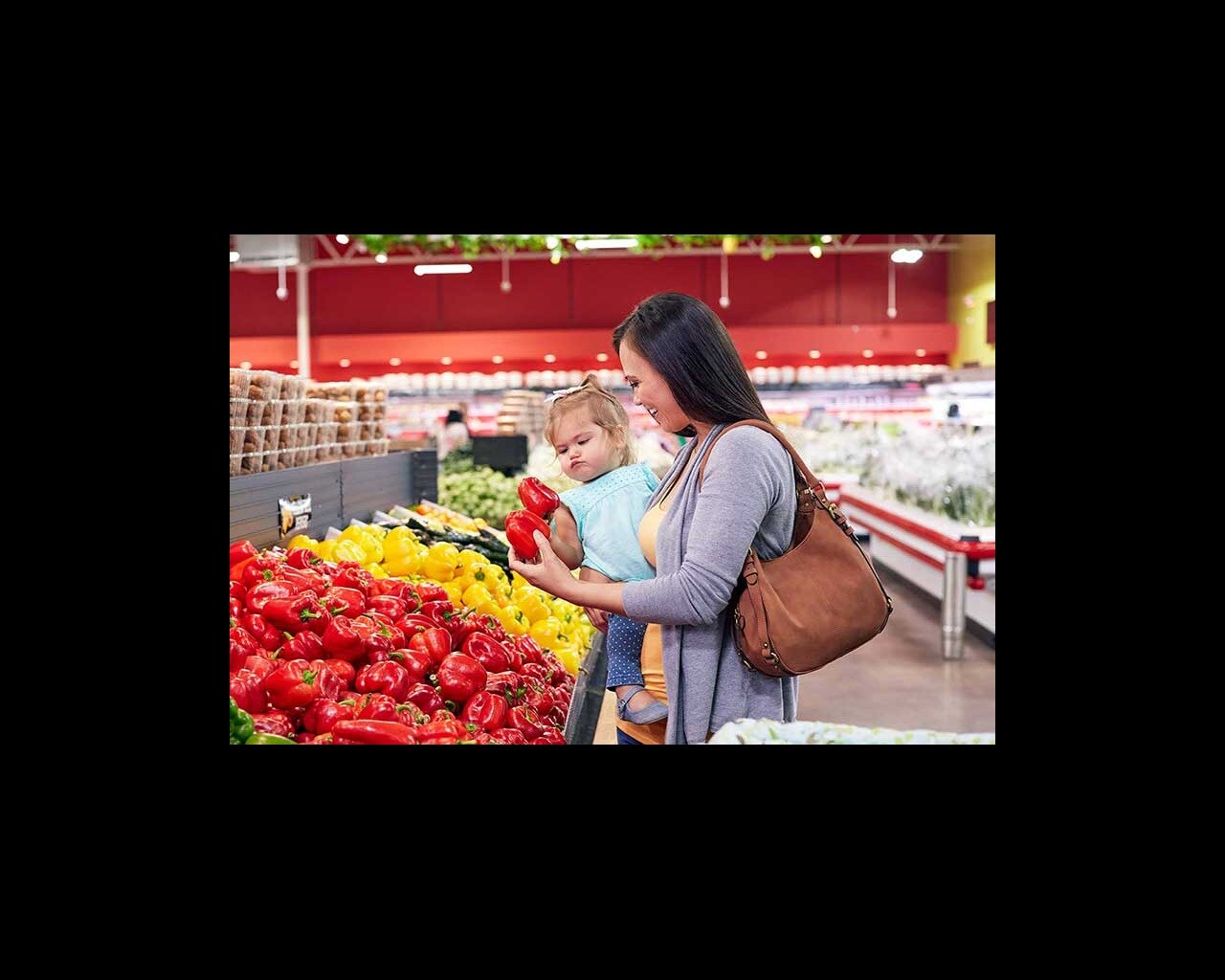 mom and toddler picking peppers in grocery store