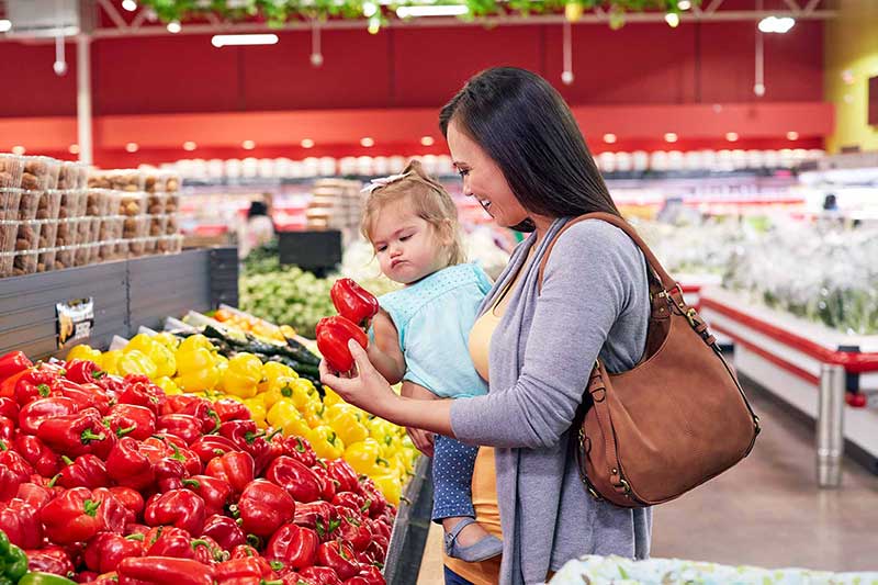 mom and toddler picking peppers in grocery store