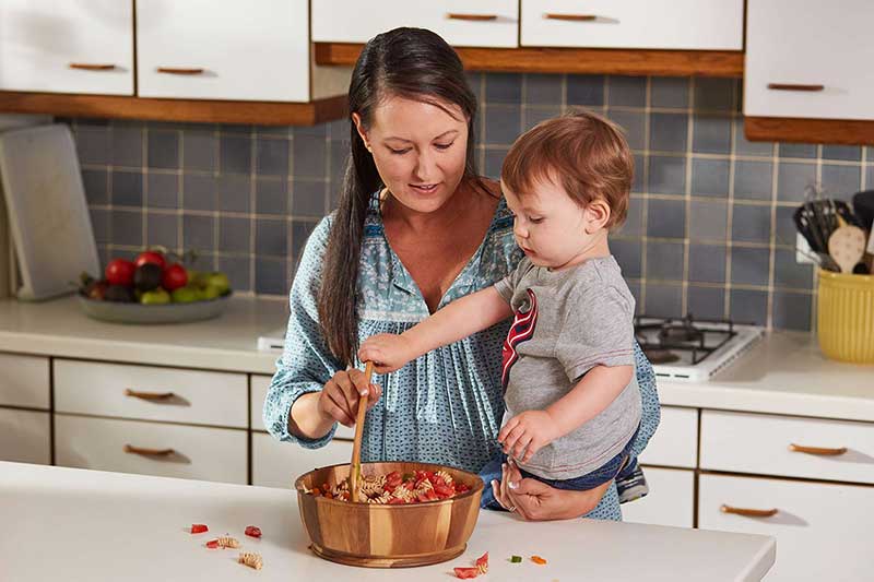 toddler helping stir in kitchen