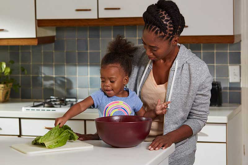 toddler tearing greens in kitchen