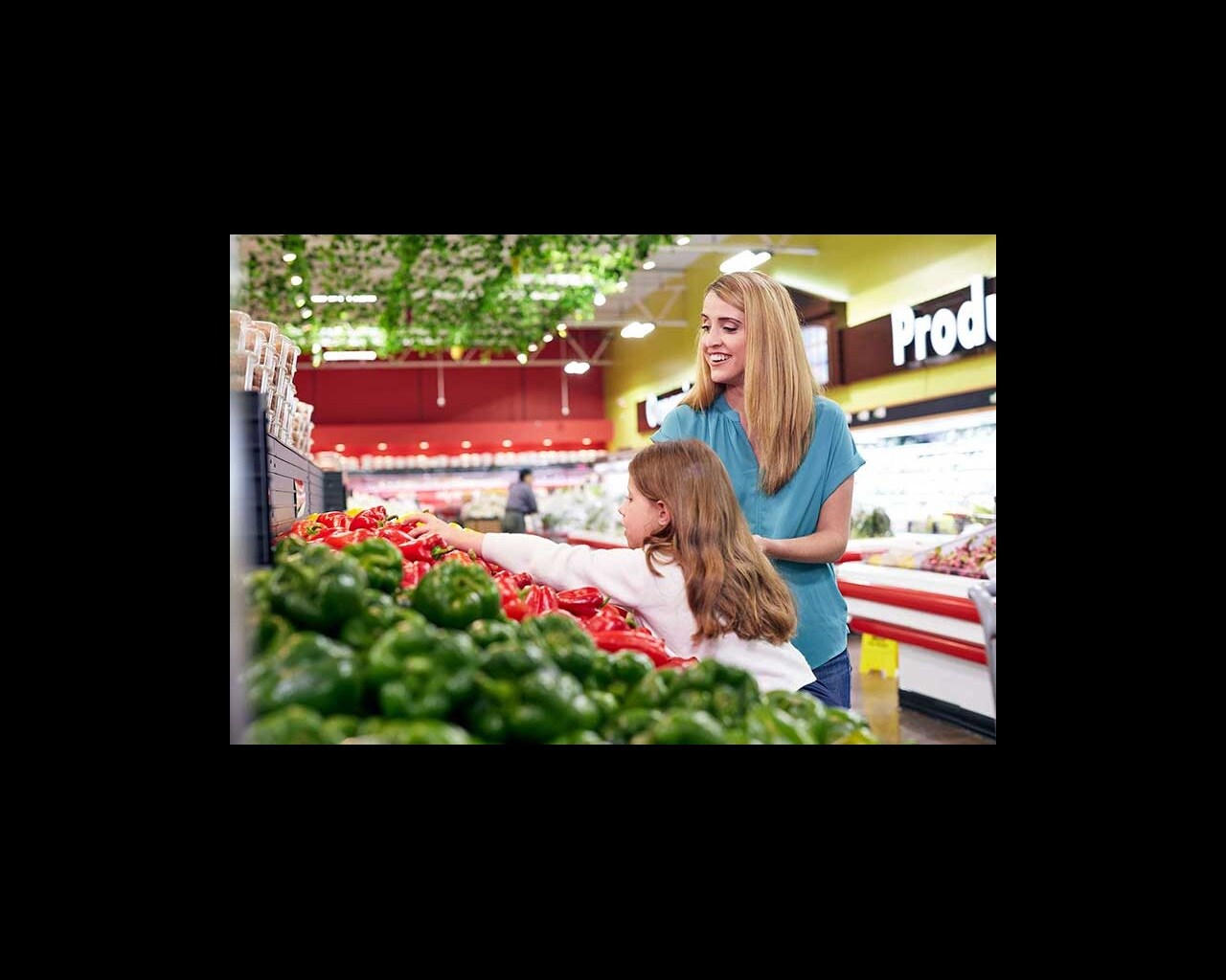 mom and daughter picking peppers in store