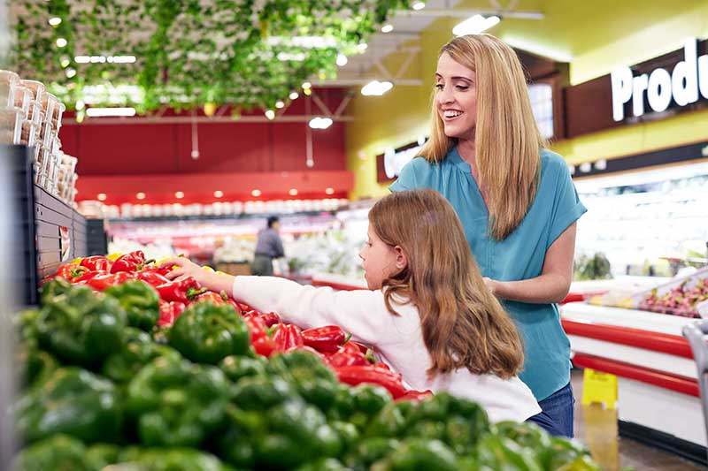 mom and daughter picking peppers in store