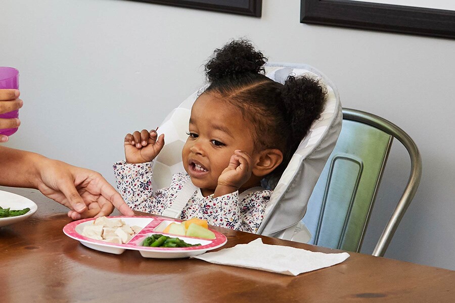 Toddler uses her hands to sign “all done” to indicate she’s finished eating
