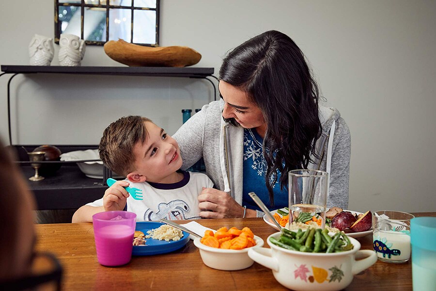 Mom and preschooler smile and talk while eating a meal at the table