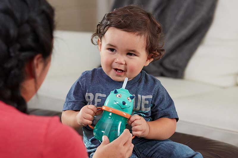 mom handing toddler straw cup of water