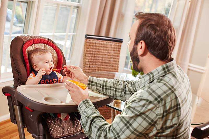 Papá alimentando a un bebé con una cuchara