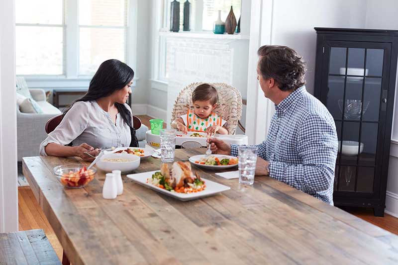 Familia comiendo en la mesa con niño pequeño. 