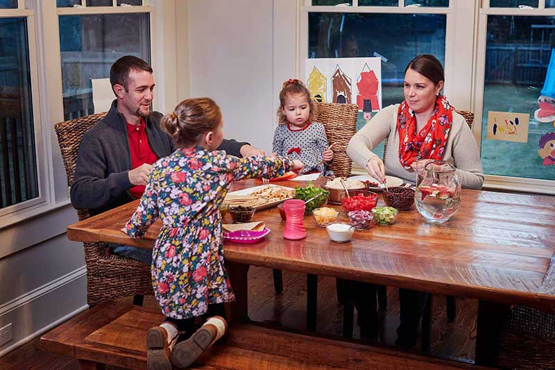 Familia comiendo en la mesa con dos niñas pequeñas