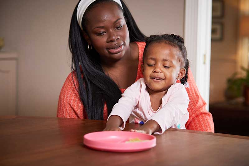 Mujer en la mesa con una niña pequeña