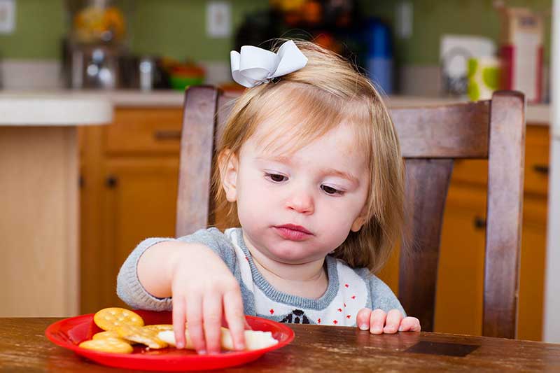 Niña pequeña comiendo un bocadillo.