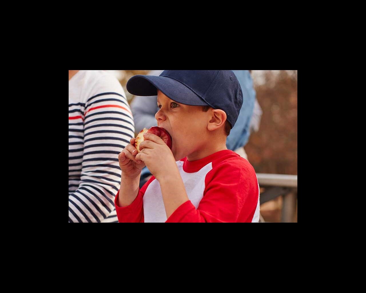 boy eating an apple at a baseball game