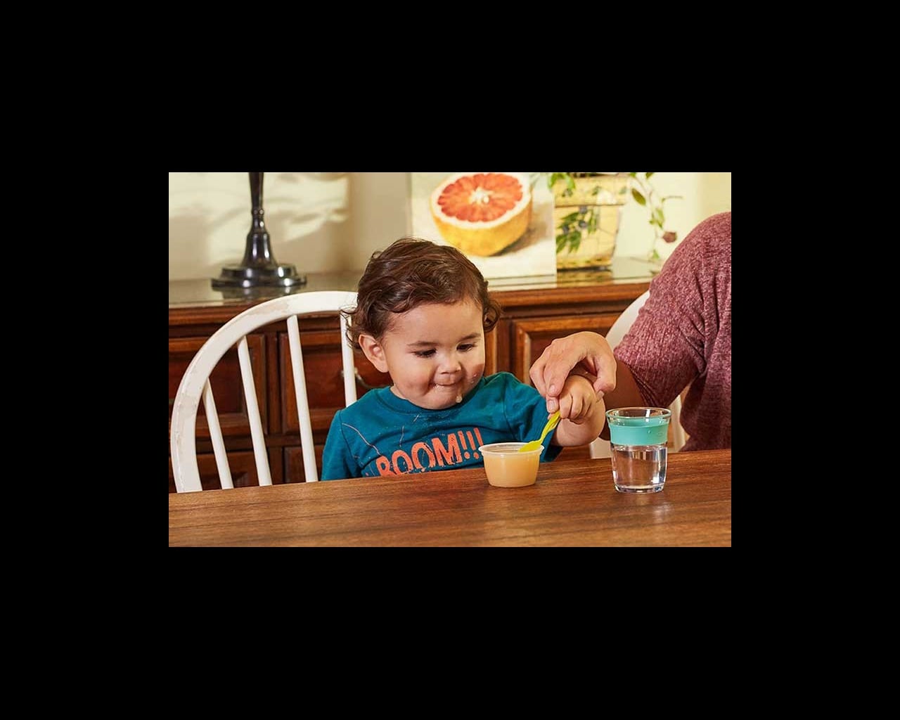 toddler reaching for spoon of applesauce