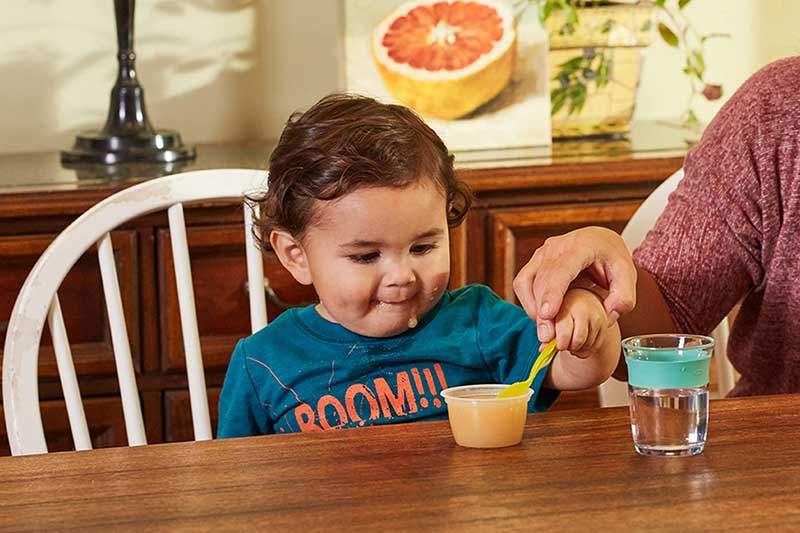 toddler reaching for spoon of applesauce