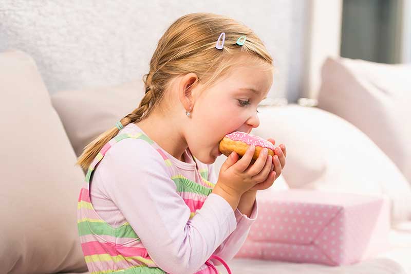 girl eating doughnut on couch