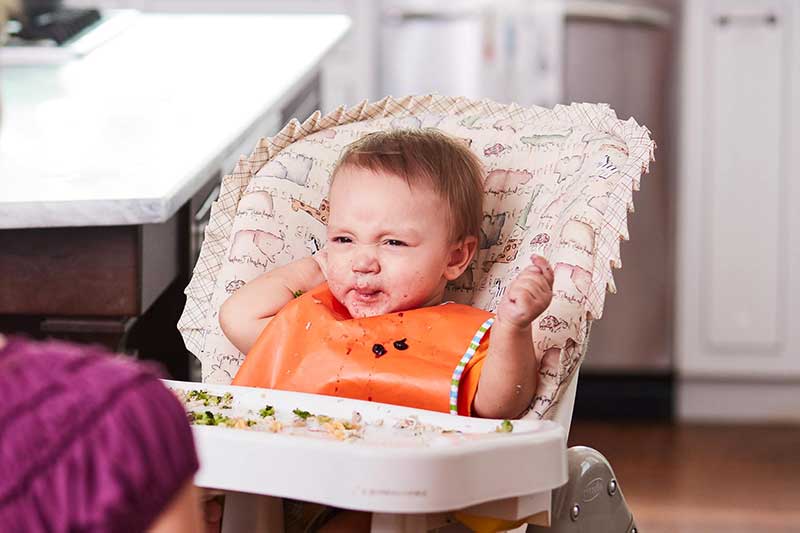 Mom feeding unhappy son