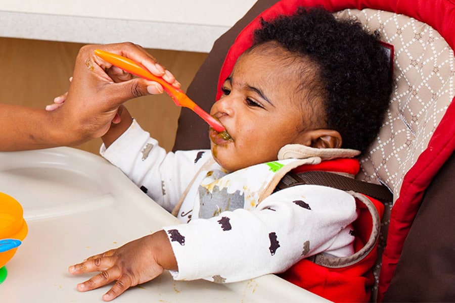 infant making funny faces eating solid food