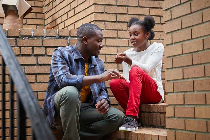 dad and daughter sitting on steps talking