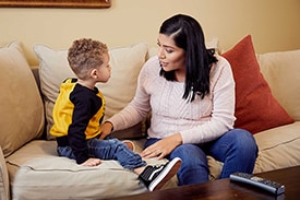 Mom sitting on the couch, talking to her toddler about body safety