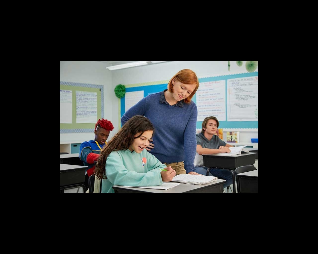 teacher helping student with homework in classroom