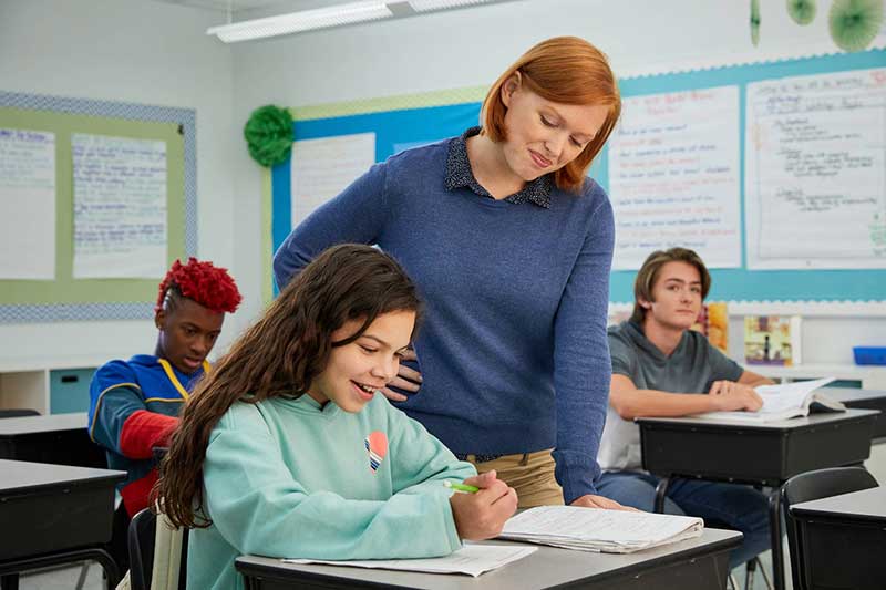 teacher helping student with homework in classroom