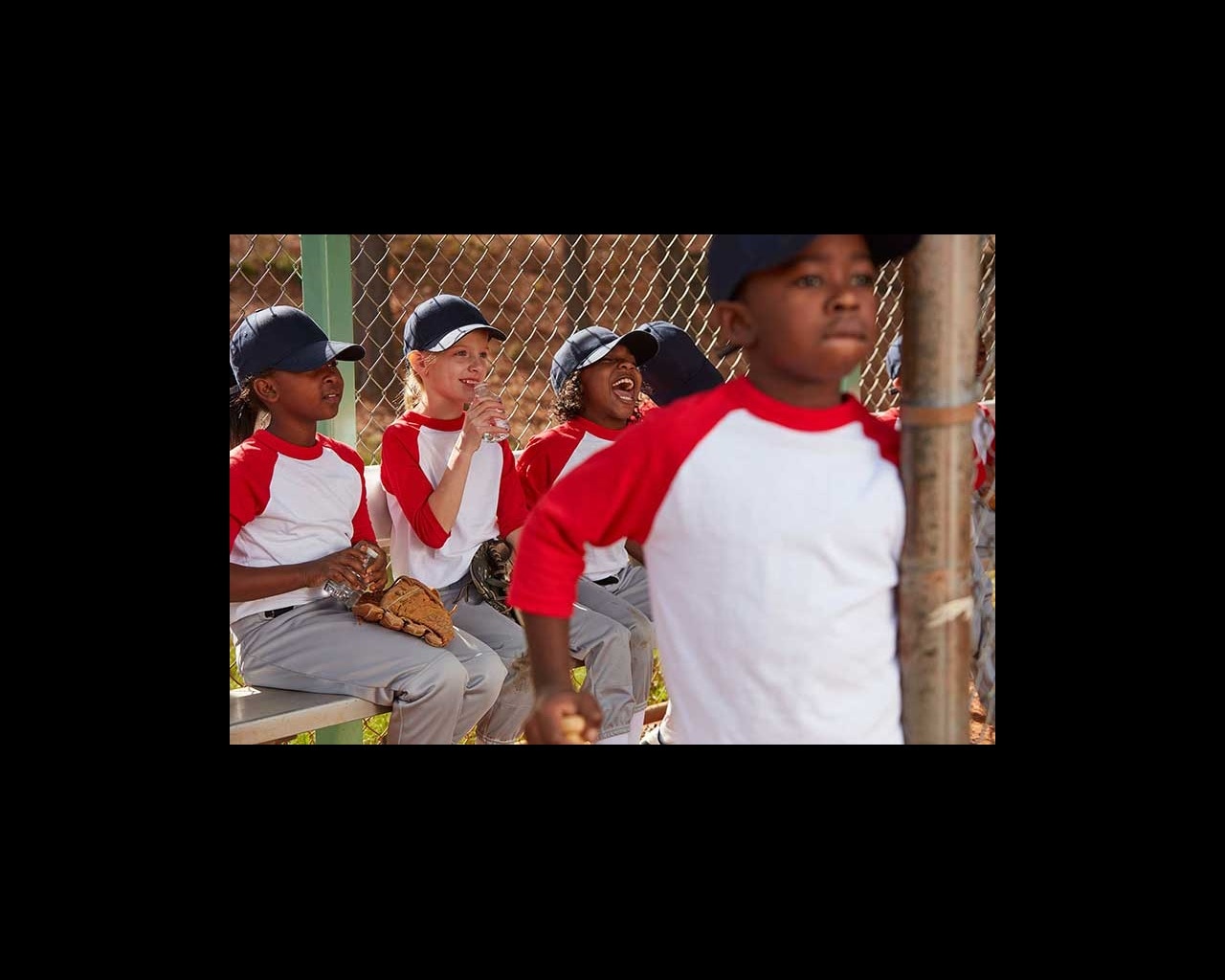 Mixed race group of young children laughing together in a baseball dugout