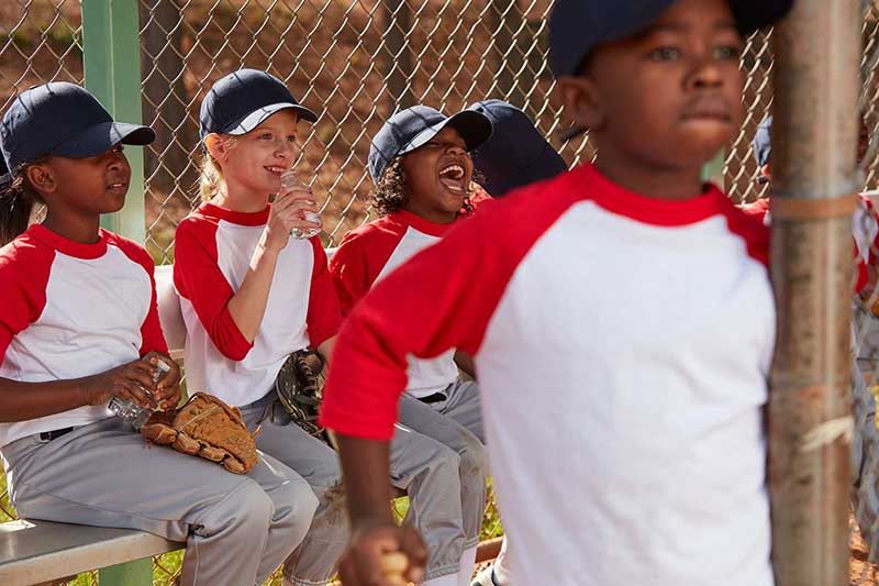 Mixed race group of young children laughing together in a baseball dugout