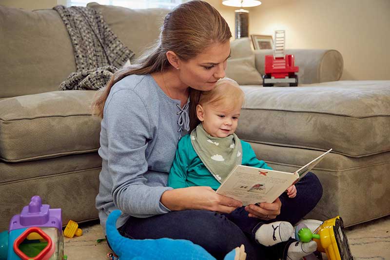 White mom reading a book to her infant son