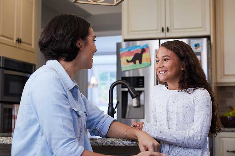 preteen girl and mom talking in kitchen