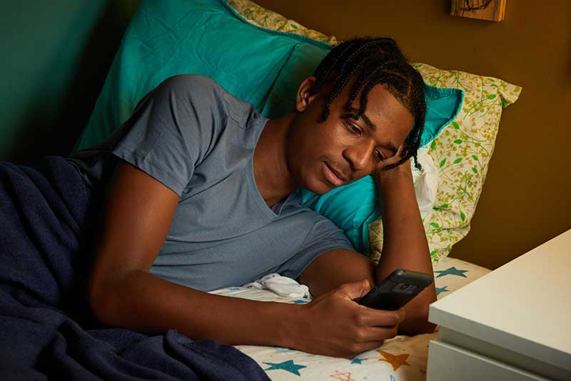 teen using phone in bed