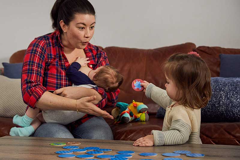 Nursing mom playing a game with older toddler