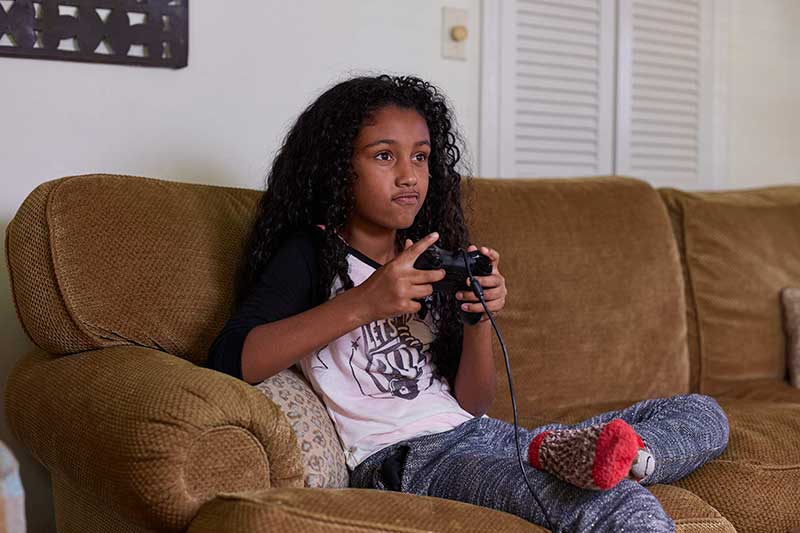 teen girl playing video game on couch