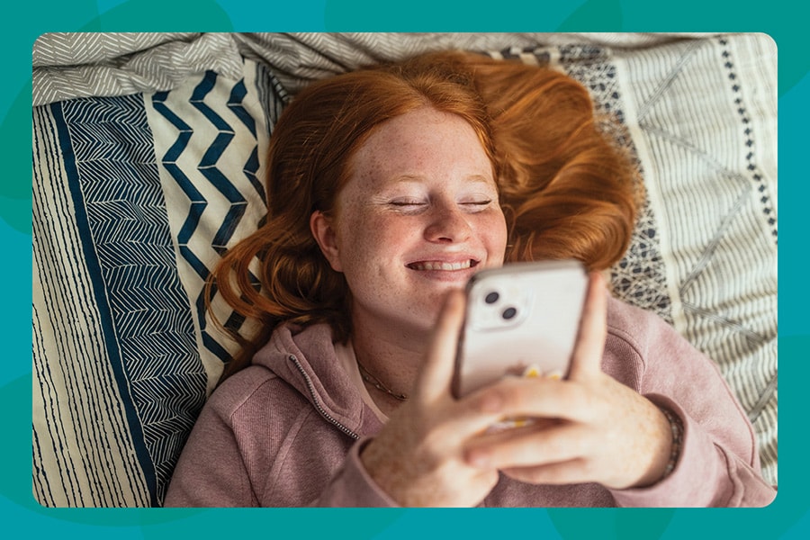 Teen girl laying on her bed playing on her phone