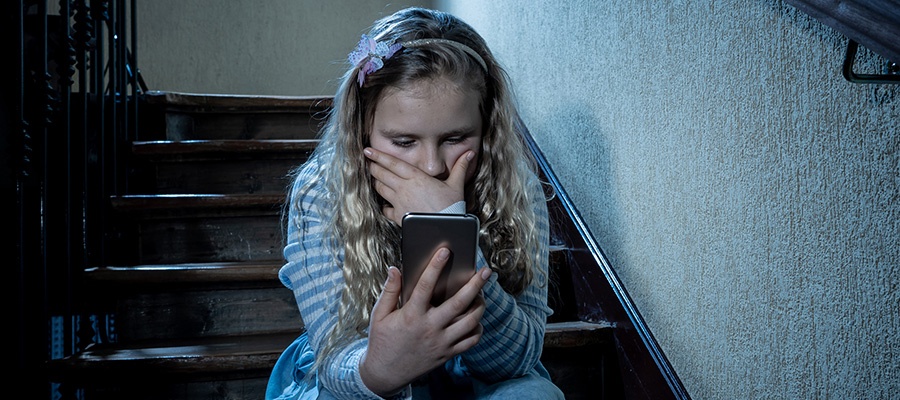 Young girl looking at a smartphone with a scared look on her face