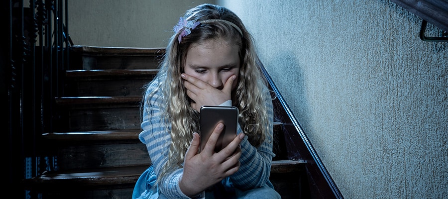Young girl looking at a smartphone with a scared look on her face