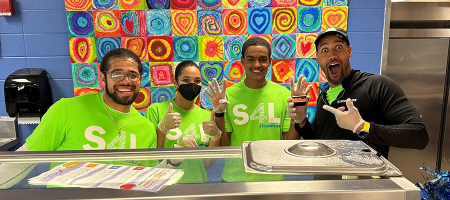 4 members of the Strong4Life Challenge Team helping serve school lunch at a follow-up visit