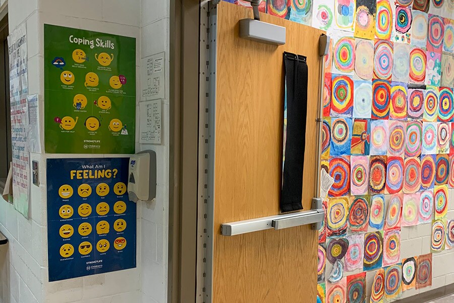 A Strong4Life coping skills poster and feelings poster hanging up on elementary school wall