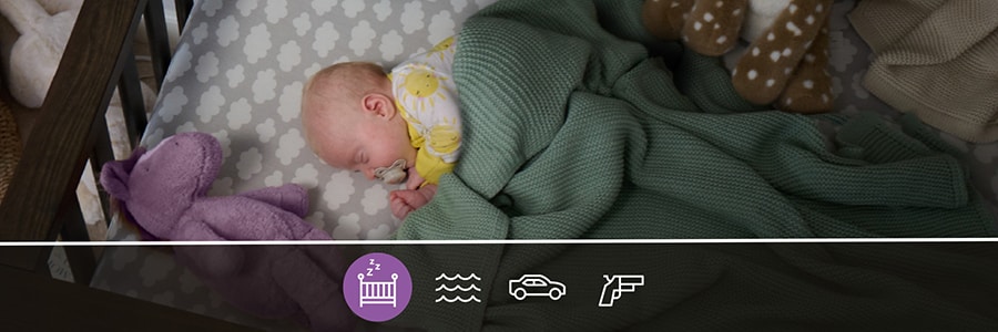 Image of baby sleeping in a crib with a blanket and toys, representing unsafe infant sleep