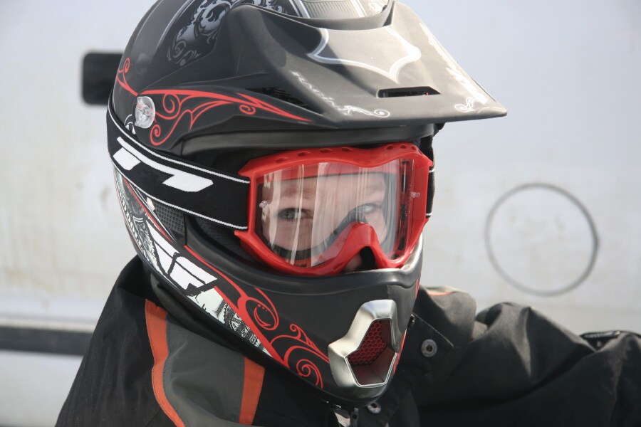 A middle schooler practices kids’ atv safety by wearing goggles and an ATV helmet.