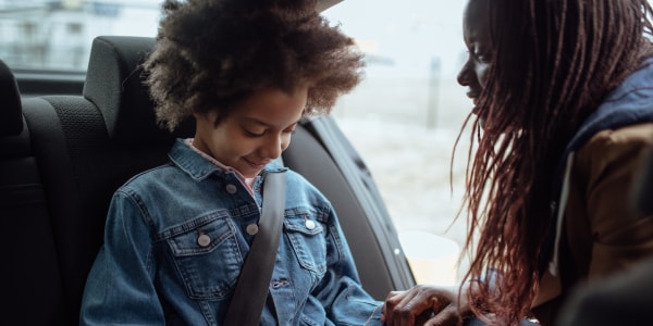 A mom helps her son safely buckle up his seat belt. 