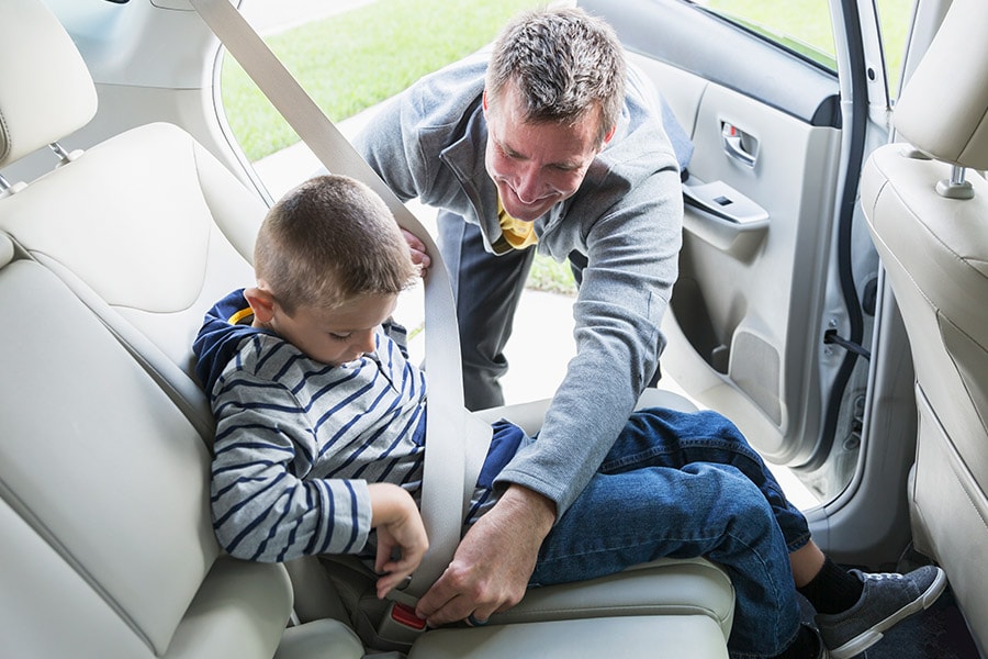 dad buckling son into seatbelt