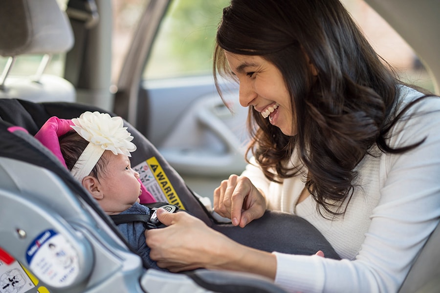 mom buckling infant into rear facing car seat