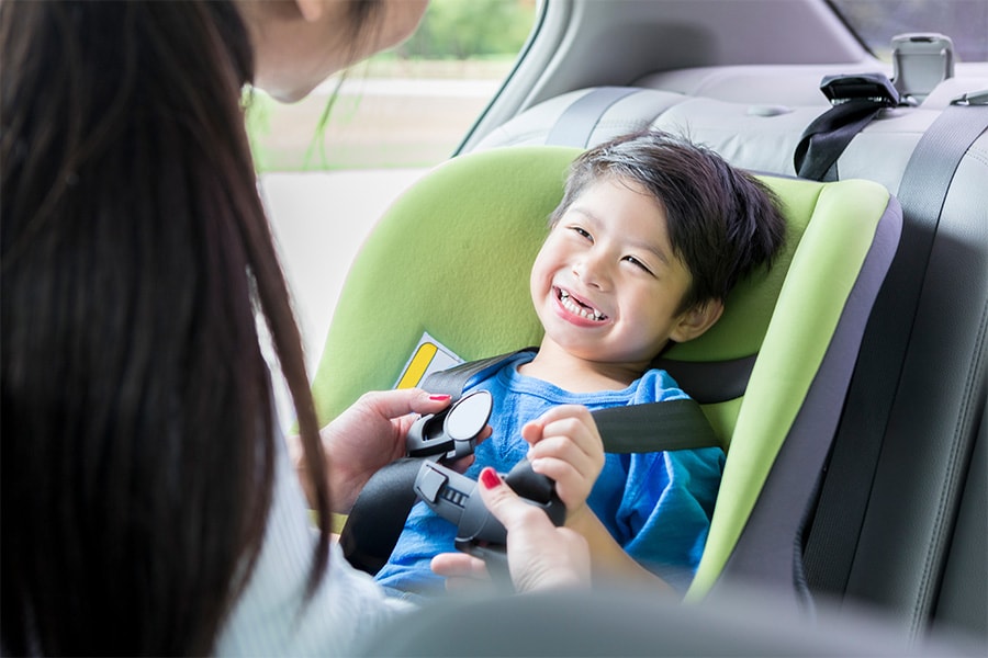 mom buckling toddler into booster seat