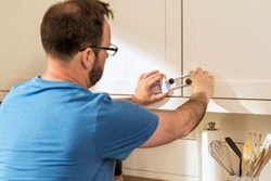 Dad putting locks on cabinet for home safety
