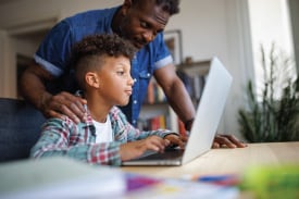  A father and son look at a laptop together.