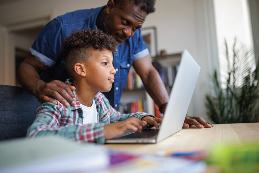  A father and son look at a laptop together.